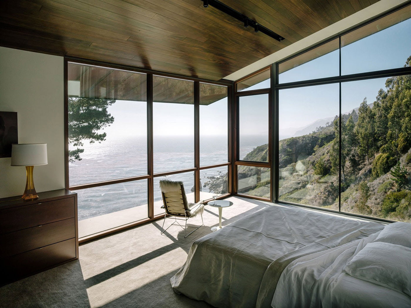 Interior de dormitorio en una casa de campo con ventanas panorámicas.