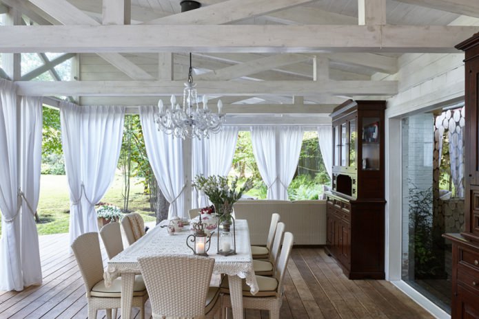 Cortinas blancas con tirantes en la terraza de una casa de campo