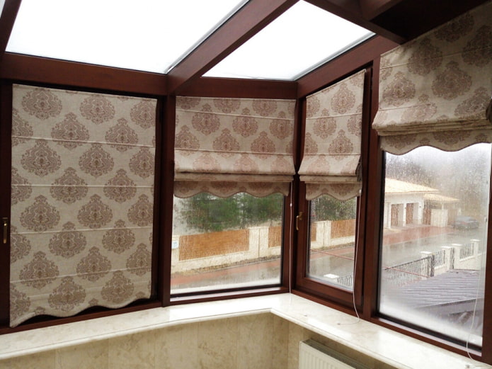 Ang Roman blinds na may monograms sa loggia