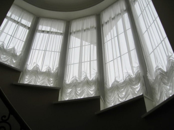 Cortinas austriacas en las ventanas a lo largo de las escaleras.