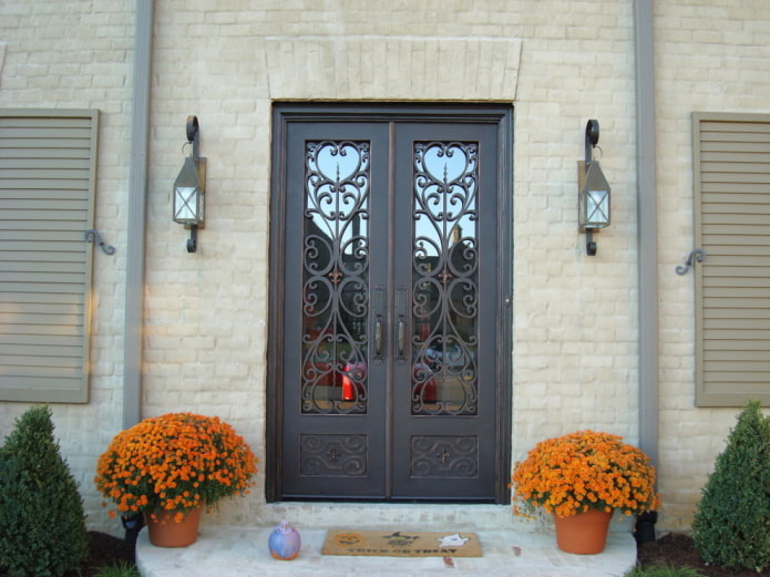 porche de una casa de campo con una puerta de entrada con hierro forjado y vidrio