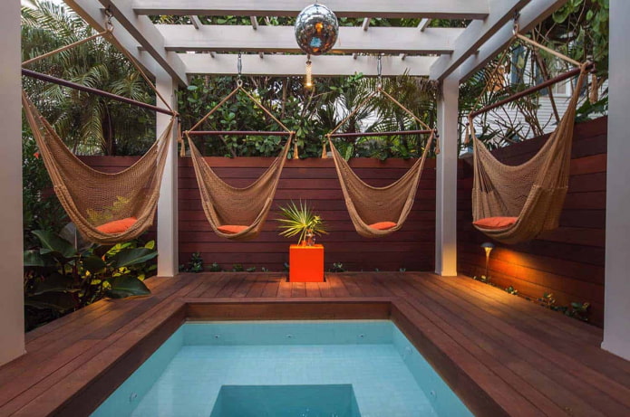 4 hamacas alrededor de la piscina con pérgola