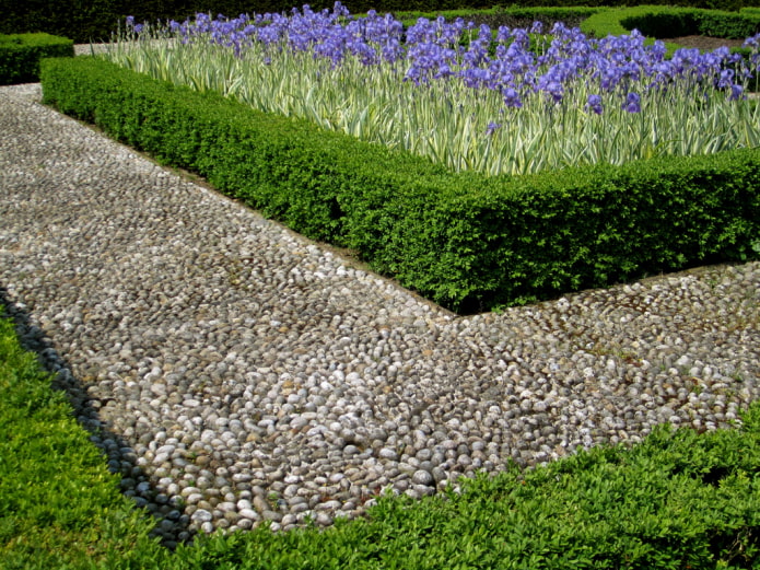 Pasarela de guijarros alrededor de un macizo de flores de lirios