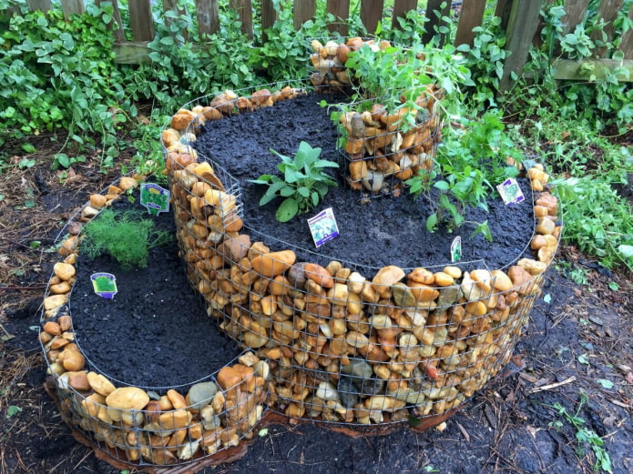 cama de flores de dos niveles con un borde de piedra en un marco de alambre