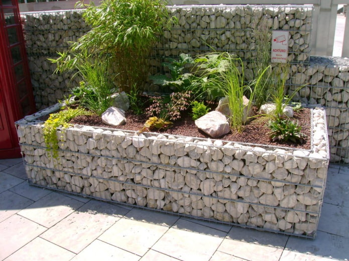 macizo de flores rectangular con un borde de piedra en un marco de alambre