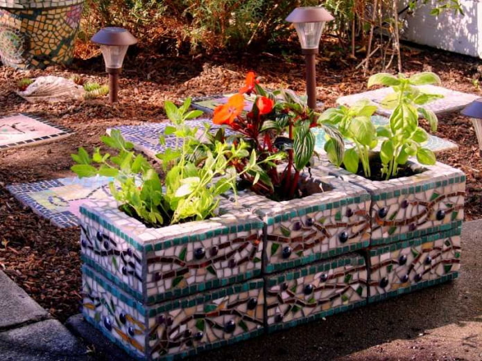 mini-macizo de flores hecho de bloques de hormigón, decorado con fragmentos de azulejos