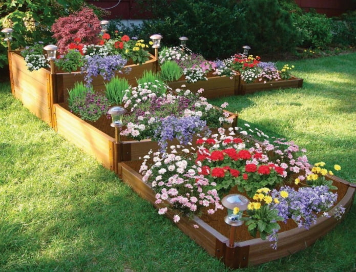 Cama de flores de tres niveles con lados de madera e iluminación.