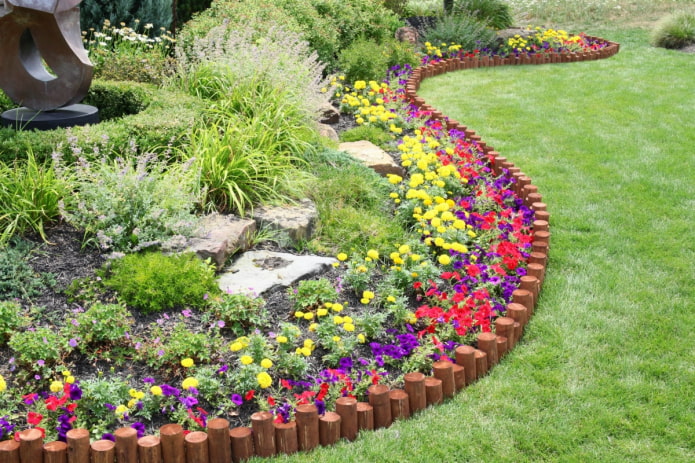 un borde para un jardín de flores hecho de estacas clavadas en diferentes profundidades