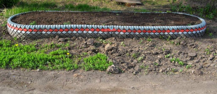 Cama de flores ovalada con un borde de corte de neumáticos y banda de rodadura pintada