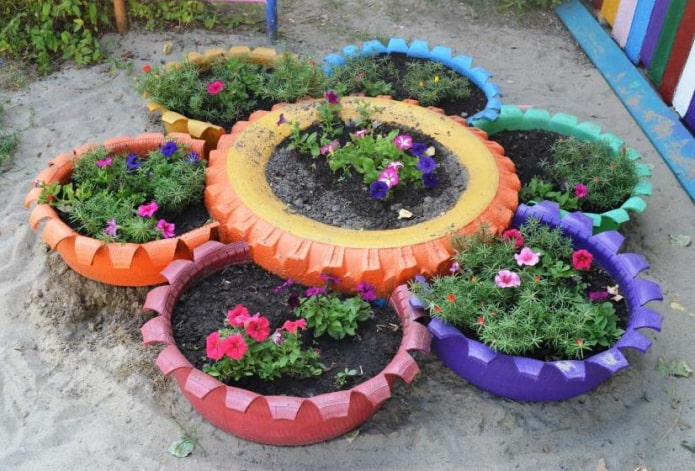 Cama de flores hecha de neumáticos pintados con dientes tallados.