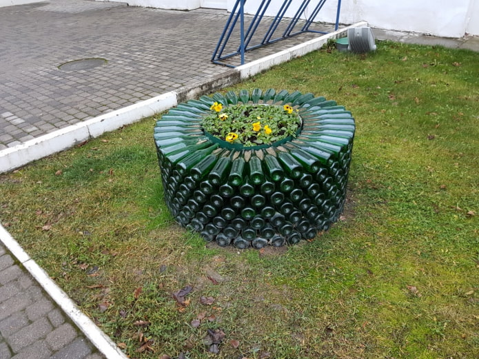 un macizo de flores redondo con un borde de botellas de vidrio apiladas una encima de la otra