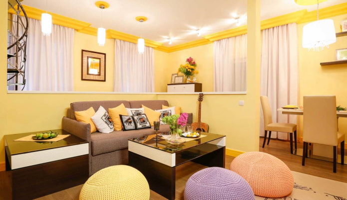 sala de estar de color amarillo claro con almohadas multicolores y otomanas de punto